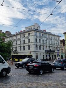 a large white building with cars parked in front of it at SOPRANO APARTMENT KRAKIVSKA 34 in Lviv