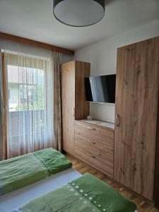 1 dormitorio con 1 cama y TV de pantalla plana en Ferienwohnungen Haus Schett, en Lienz