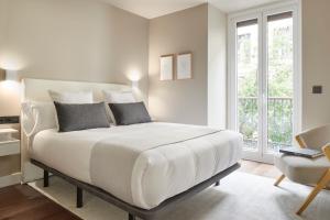 a white bedroom with a bed and a chair at Elkano by FeelFree Rentals in San Sebastián