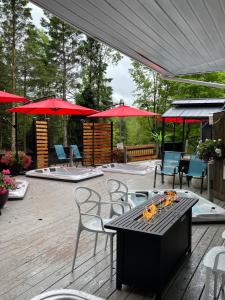 un patio con tavoli, sedie e ombrelloni rossi di Auberge Hotel Spa Watel a Sainte-Agathe-des-Monts Altre 174 foto