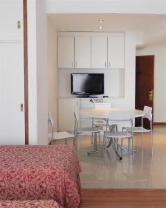 Zimmer mit einem Tisch, Stühlen und einem TV in der Unterkunft Hotel Guerrero in Mar del Plata