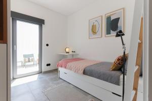 a white bedroom with a bed and a window at Casa Alegra in Carvalhal