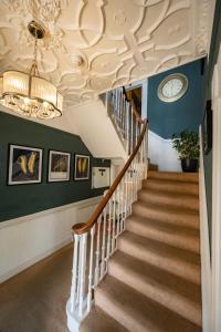 una escalera en una casa con una lámpara de araña en The Bramley House Hotel en Chatteris