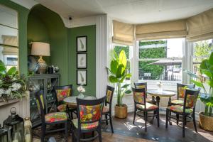 comedor con paredes verdes, mesa y sillas en The Bramley House Hotel en Chatteris
