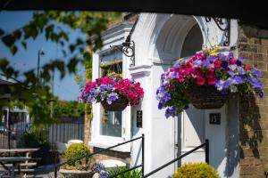 deux paniers de fleurs sur le côté du bâtiment dans l'établissement The Bramley House Hotel, à Chatteris