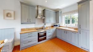 a kitchen with white cabinets and an orange tile floor at Bunkers Hill Cottage in Tackley