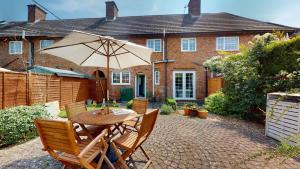 a table and chairs with an umbrella in front of a house at Bunkers Hill Cottage in Tackley