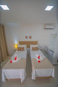 Cette chambre comprend 3 lits avec des fleurs. dans l'établissement Pousada Polymar, à Maragogi