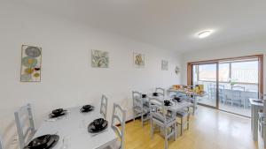 une salle à manger avec des tables et des chaises blanches dans l'établissement We Are Hostel 2, à Póvoa de Varzim