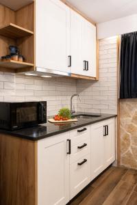 a kitchen with white cabinets and a plate of fruit at Mathraki Resort in Gouvia