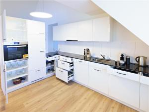 a white kitchen with white cabinets and a wooden floor at Exklusive 4.5 Zimmer Wohnung für Familien und Business in Eschenz