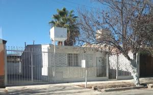 uma cerca em frente a um edifício branco em IAUE EL HOGAR, una habitacion cocina,baño, estacionamiento compartido y patio em Luján de Cuyo