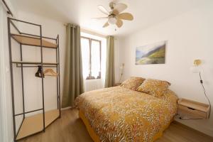 1 dormitorio con 1 cama y ventilador de techo en La Petite Maison du Périgord, en Tourtoirac