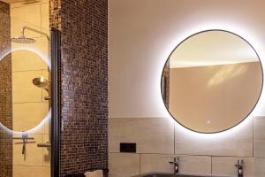 een badkamer met een grote ronde spiegel aan de muur bij Het Oude Stadhuis in Enschede