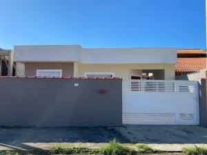 une maison avec une porte blanche et une clôture dans l'établissement Casa dos Andrade em Caraguatatuba, à Caraguatatuba