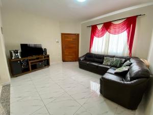 - un salon avec un canapé en cuir et une télévision dans l'établissement Casa dos Andrade em Caraguatatuba, à Caraguatatuba
