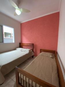 - 2 lits dans une chambre dotée d'un mur rouge dans l'établissement Casa dos Andrade em Caraguatatuba, à Caraguatatuba