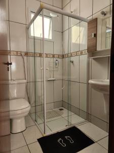 La salle de bains est pourvue d'une douche en verre, de toilettes et d'un lavabo. dans l'établissement Casa dos Andrade em Caraguatatuba, à Caraguatatuba