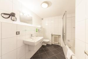 a white bathroom with a sink and a toilet at Hotel Drei Kronen Elmshorn in Elmshorn