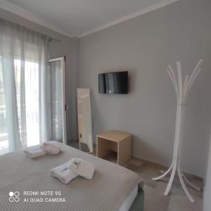 a white bedroom with a bed and a tv on the wall at Nafsika in Ammouliani