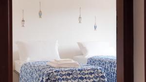 a bedroom with two beds with blue and white sheets at VILLA TO' in Àrbatax