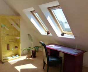 ein Büro im Dachgeschoss mit einem Schreibtisch und Fenstern in der Unterkunft Loft Sierksdorf in Sierksdorf