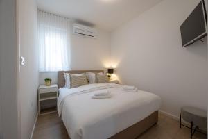a white bedroom with a large bed and a television at Villa Bepo in Plano