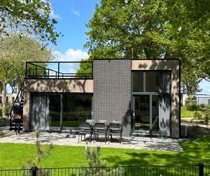 a house with glass doors and chairs in a yard at Traum Ferienhaus mit Dachterrasse am Veluwemeer in Hulshorst