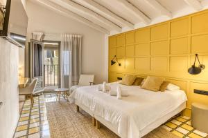 a bedroom with a white bed and a yellow wall at Mas Cusi in Palau-Saverdera