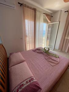 een slaapkamer met een bed met roze lakens en een raam bij Relax Rental in Vlorë