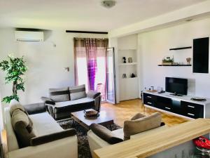 a living room with couches and a flat screen tv at City view & pool apartment in Niš