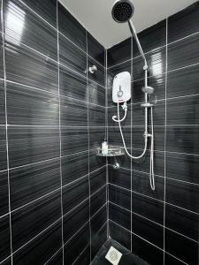 a shower in a bathroom with black tiles at Naam Boutique Lodge in Port Dickson