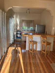 a kitchen with wooden floors and a counter with two chairs at Seacret Studios - Cozy Jamaican Retreat apts in Negril