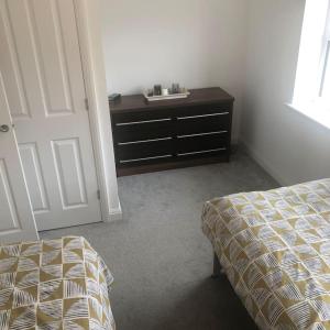 ein Schlafzimmer mit einem Bett und einer Kommode neben einer Tür in der Unterkunft Entire 2 bedroom house in Tamworth in Tamworth