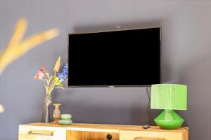 a tv on a wall with a table with a lamp at Textielfabriek Jannink in Enschede