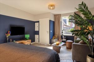 een slaapkamer met een bed, een bank en een tv bij Textielfabriek Jannink in Enschede