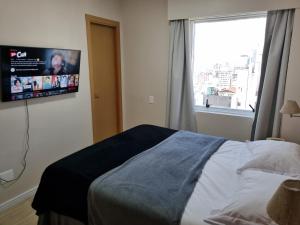 a bedroom with a bed and a tv on the wall at Apartamento Vista Maravilhosa - Próximo da Paulista in Sao Paulo