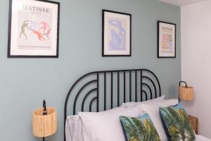 a bedroom with a bed with four framed pictures on the wall at X-Large two bedroom & two bathroom apartment with free evening parking in Southampton