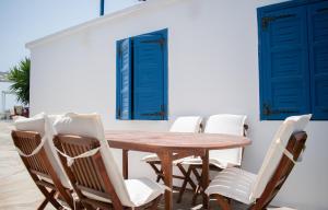 una mesa de madera y sillas con puertas y ventanas azules en Aeraki Studios en Kastraki