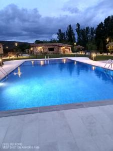 a large swimming pool with blue water at night at Las Villas de Fuentidueña in Fuentidueña
