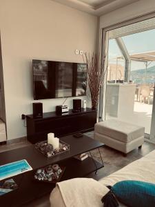 een woonkamer met een tv en een bank en een tafel bij Kapsalakis Penthouse in Korinthos