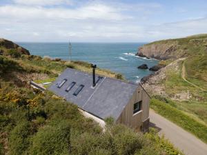 a small house on a hill next to the ocean at Cliff-top Cottage on Coast Path w/Panoramic Views in Trevine