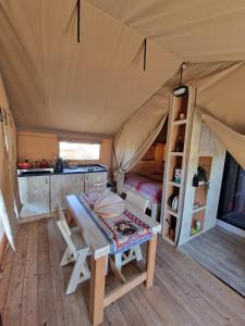 Una habitación con una mesa y una cama en una tienda de campaña en Tendu' Punta Bianca Glamping Camp, en Palma di Montechiaro