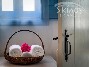 a basket filled with towels and a pink flower at Traditional Maisonette with picturesque Chora View in Chora Folegandros