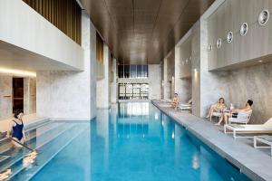 a pool in a building with people sitting around it at A Cozy & Lux Apt Next to Southern Cross Station in Melbourne