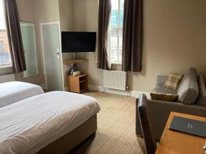 a hotel room with a bed and a couch and a tv at The Oxnoble in Manchester