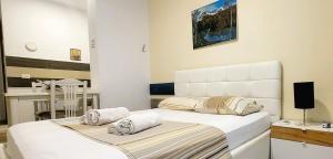 a white bedroom with a bed and a desk at Studenti Studio's in Tirana
