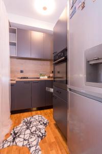 a kitchen with stainless steel appliances and a wooden floor at Apartment FiVe Visoko in Visoko