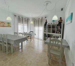 a dining room with tables and chairs and a book shelf at Hostel Conil in Conil de la Frontera