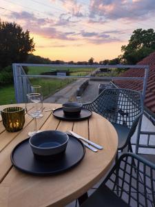 - une table en bois avec 2 assiettes et des verres à vin dans l'établissement Vakantiehuisje Fie, à Dilsen-Stokkem
